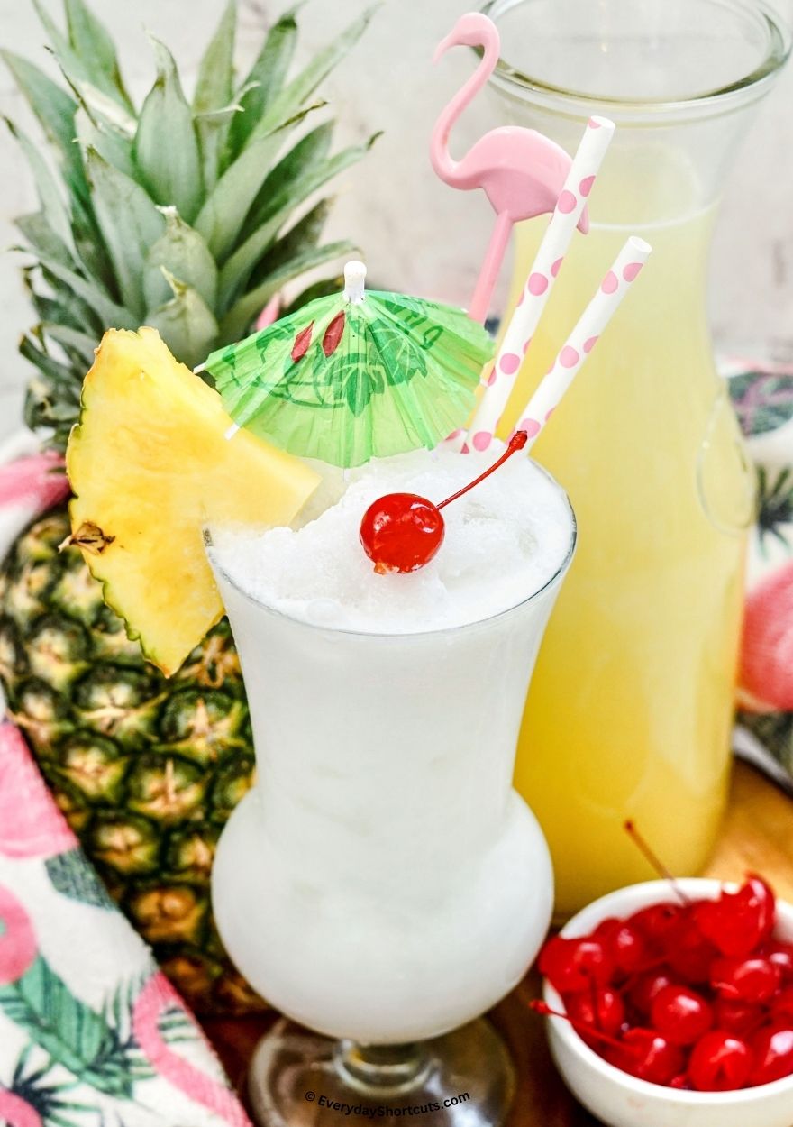 frozen pina colada in a hurricane glass with a pink flamingo cocktail pick