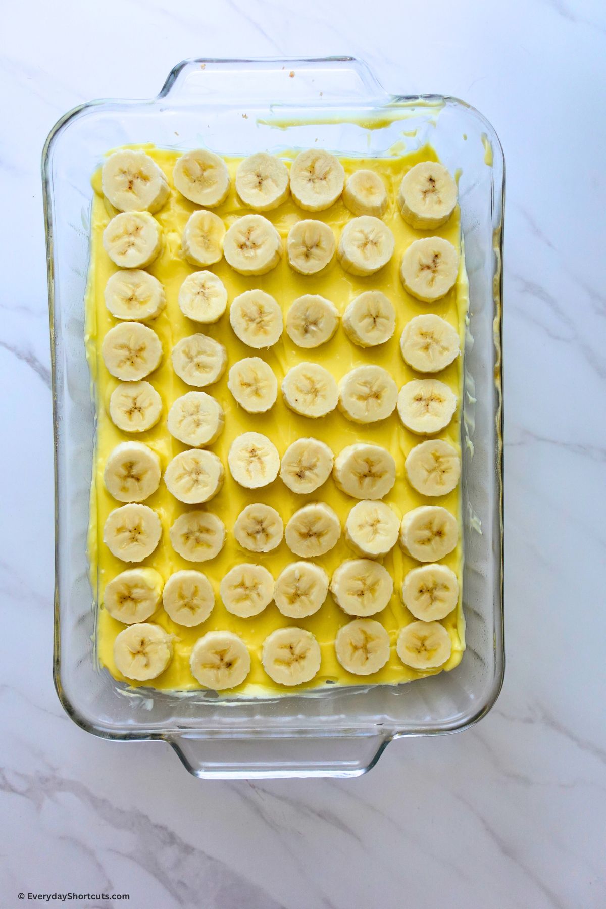 sliced bananas on top of creamy pudding layer in baking dish