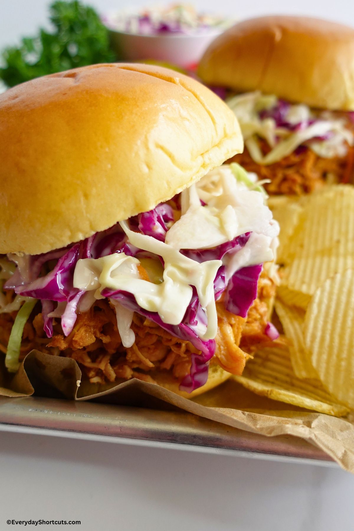 pulled chicken sandwiches on a tray with potato chips