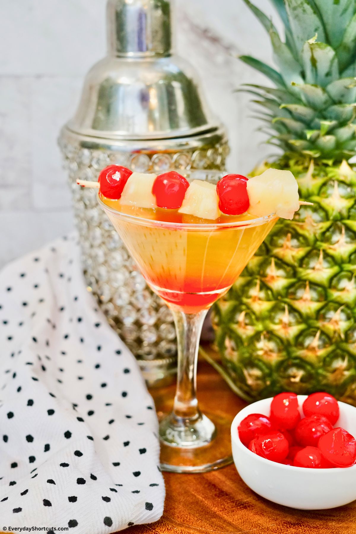 layered summer cocktail garnished with cherries and pineapple