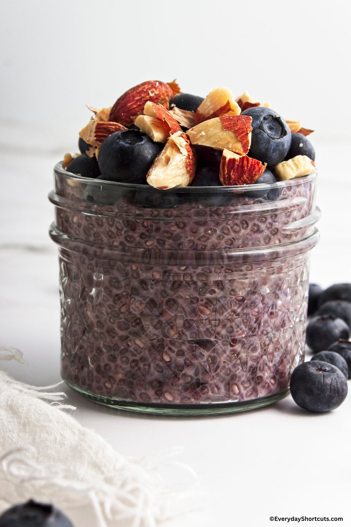 blueberry chia pudding in a jar with nuts and blueberries