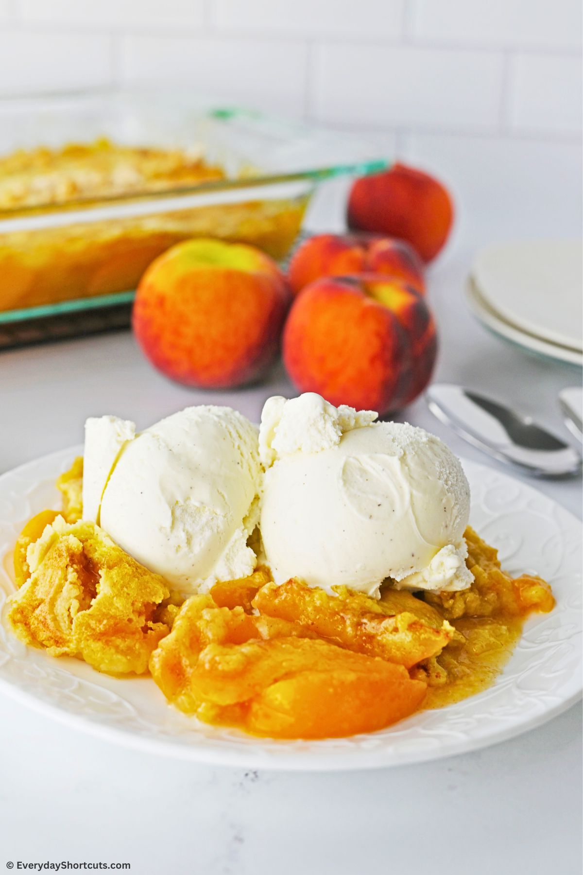 peach dump cake on a plate with two scoops of ice cream on top