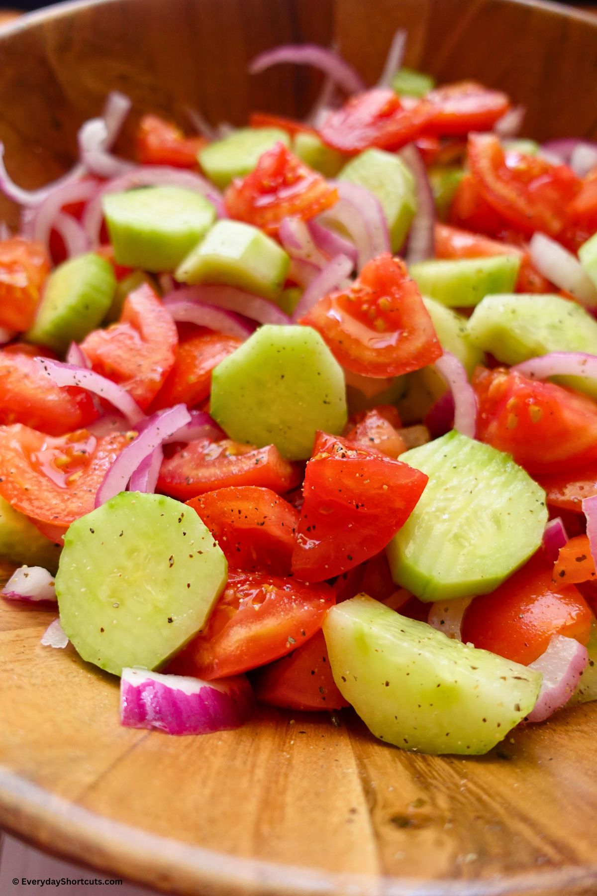 tomatoes onions and cucumbers seasoned with salt and pepper in a bowl