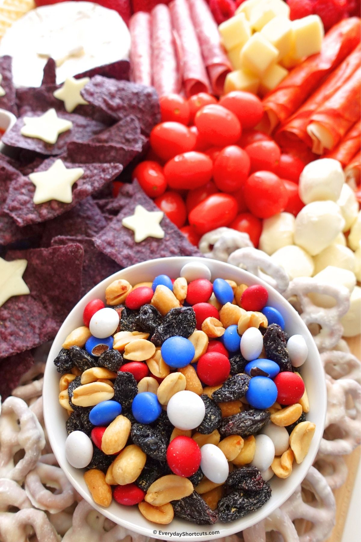 red white and blue trail mix in a bowl on a charcuterie board