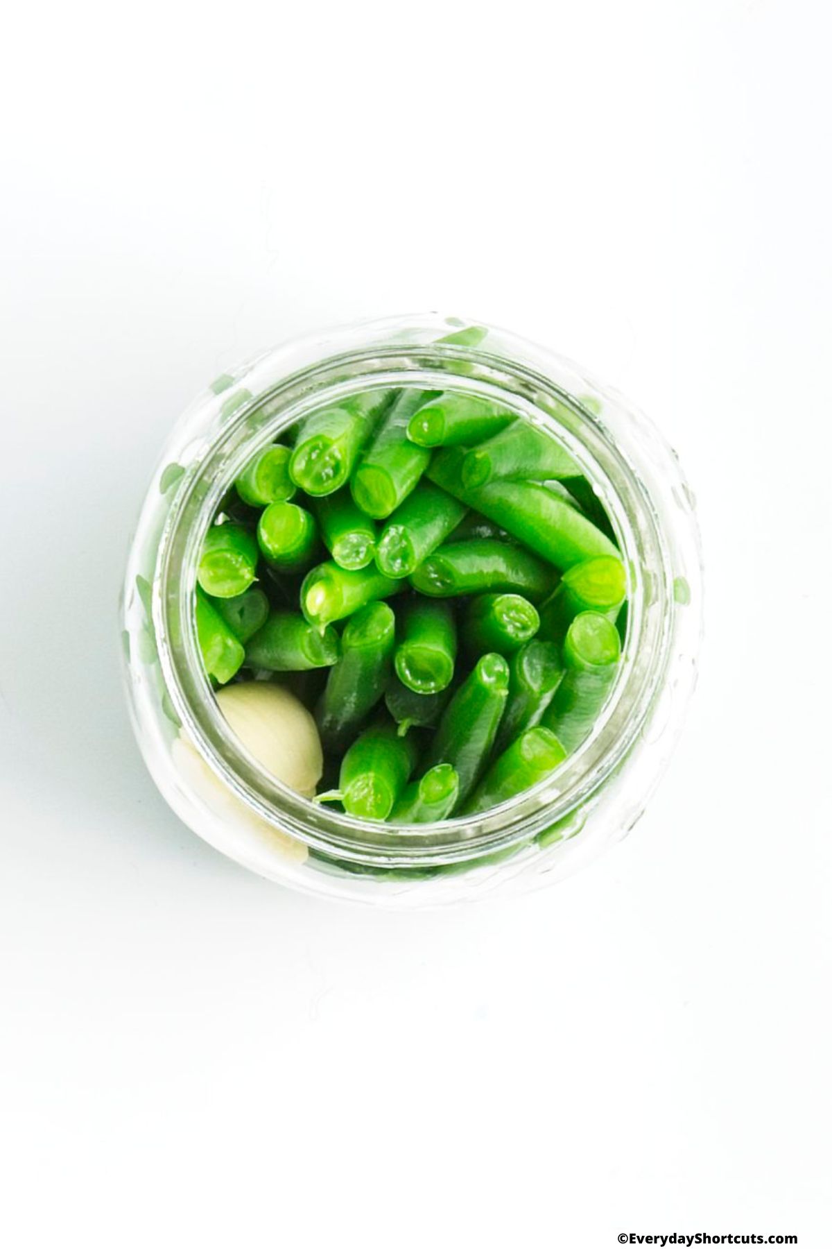 blanched green beans in a mason jar with a garlic clove