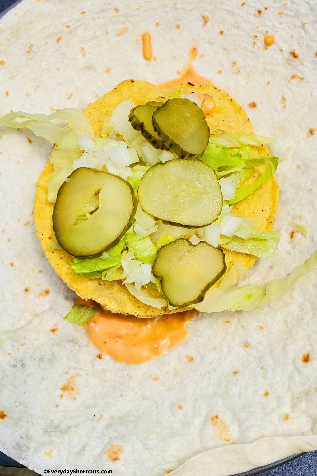 dill pickles on top of toppings on crunchy tortilla