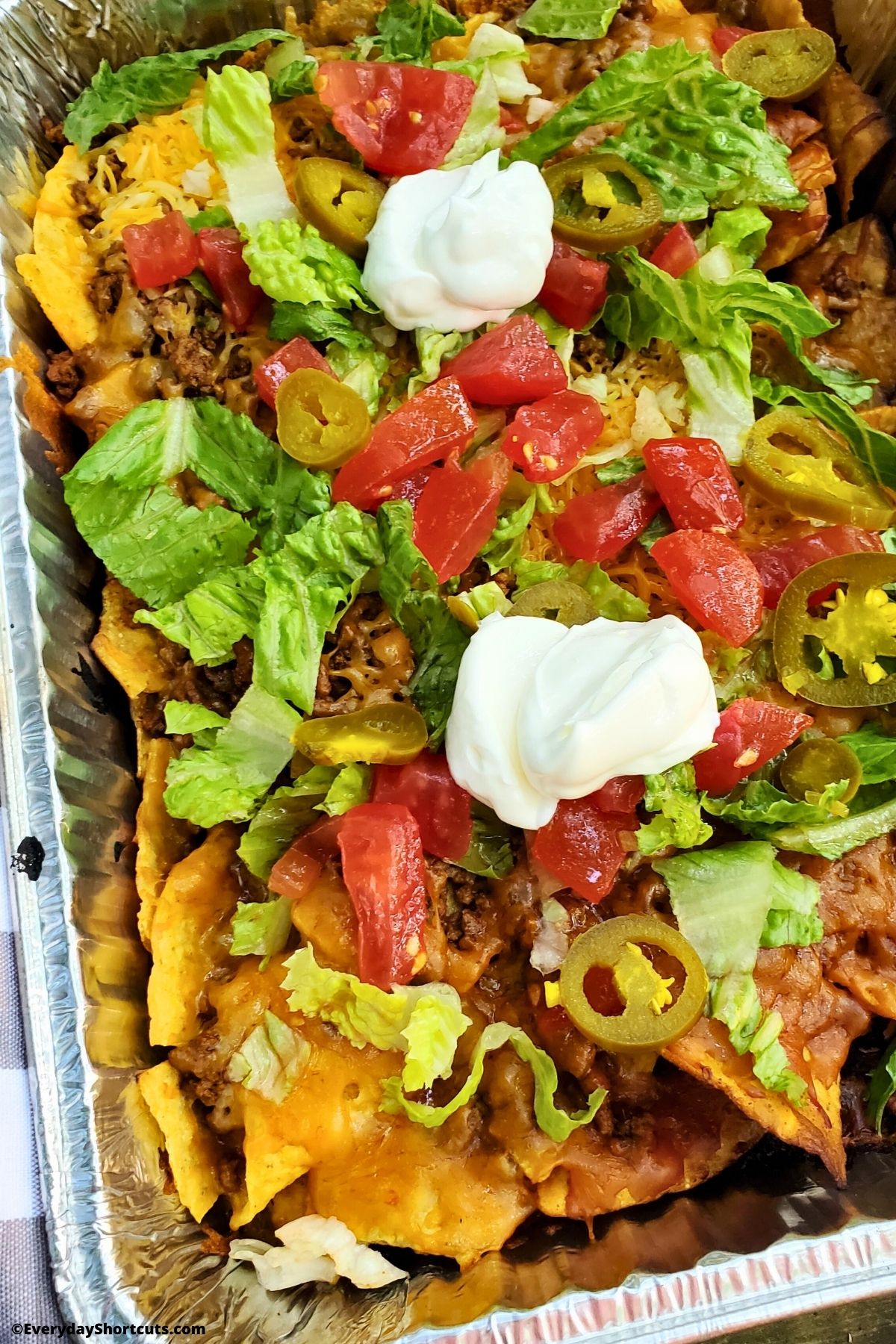 campfire nachos in a foil pan with toppings