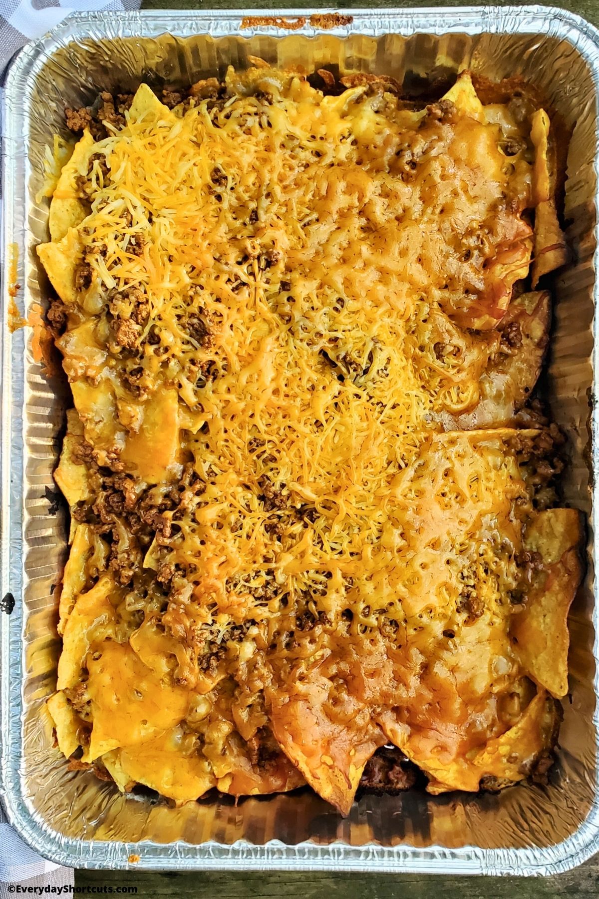 nachos with melted cheese in a disposable pan