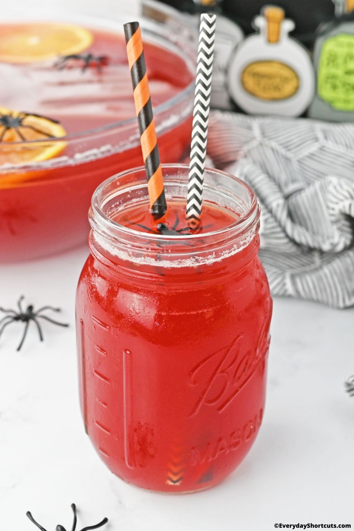 red vodka drink in a glass with straws and plastic spiders
