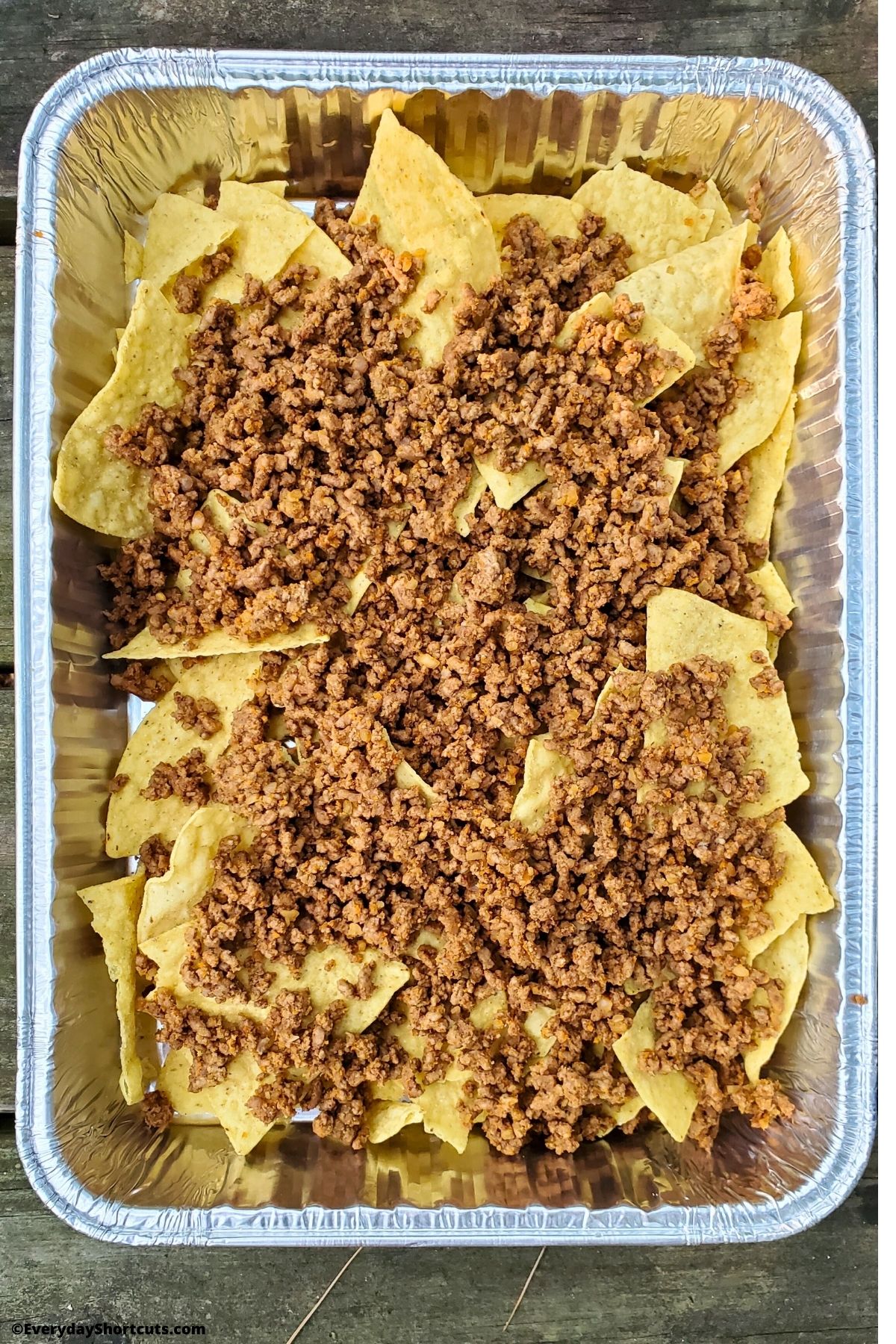 taco meat on tortilla shells in a foil pan