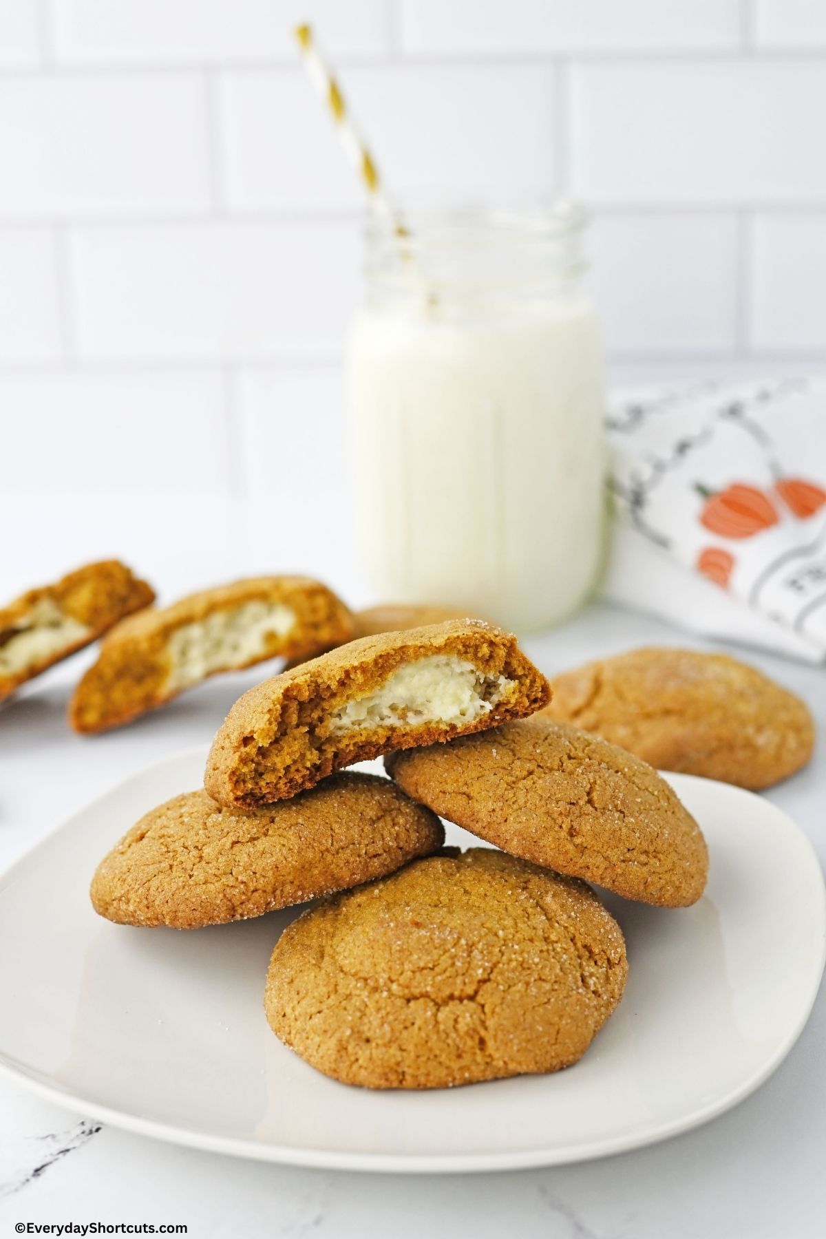 stack of cheesecake stuffed pumpkin cookies on a plate with milk