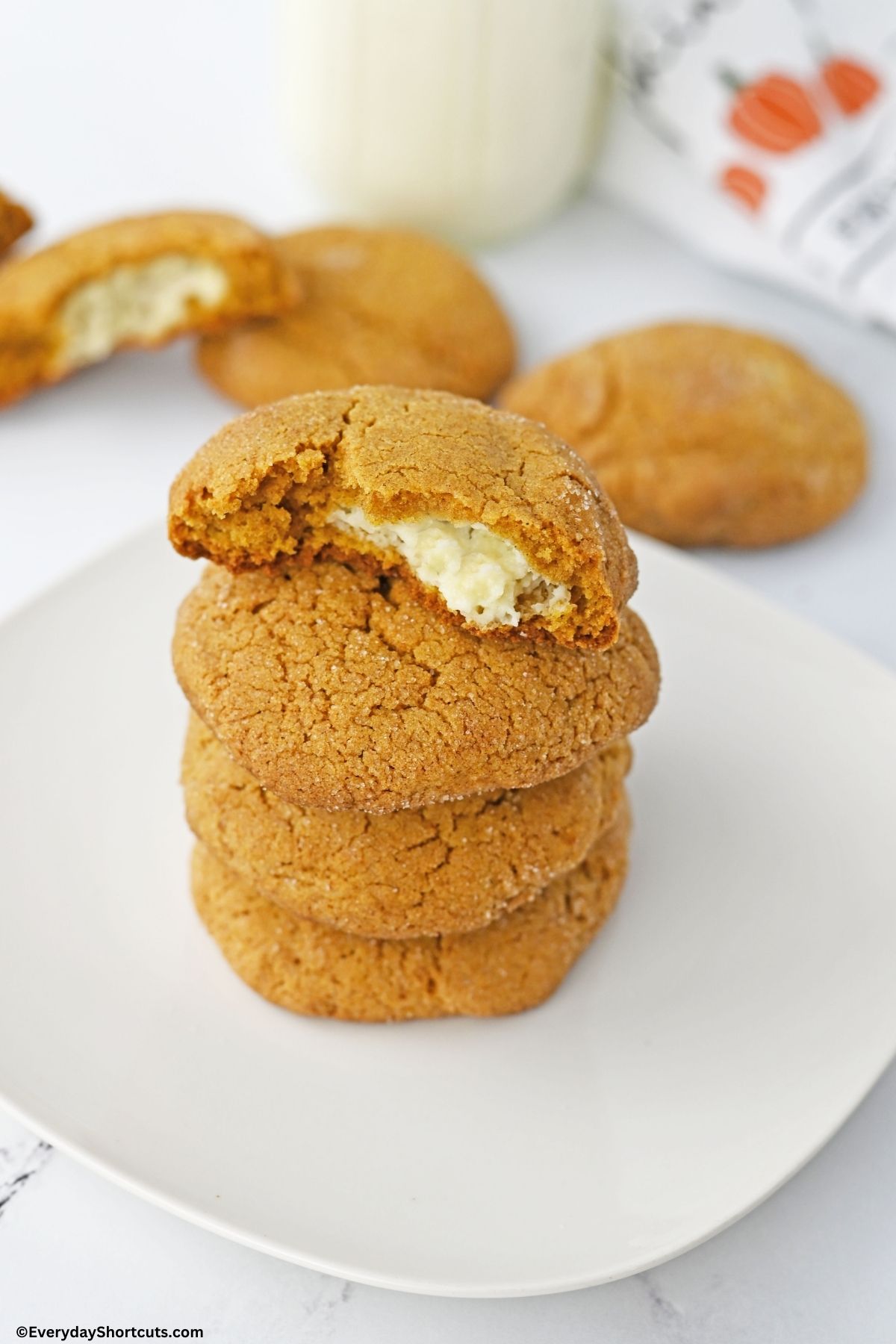 stacked pumpkin stuffed cheesecake cookies on a plate