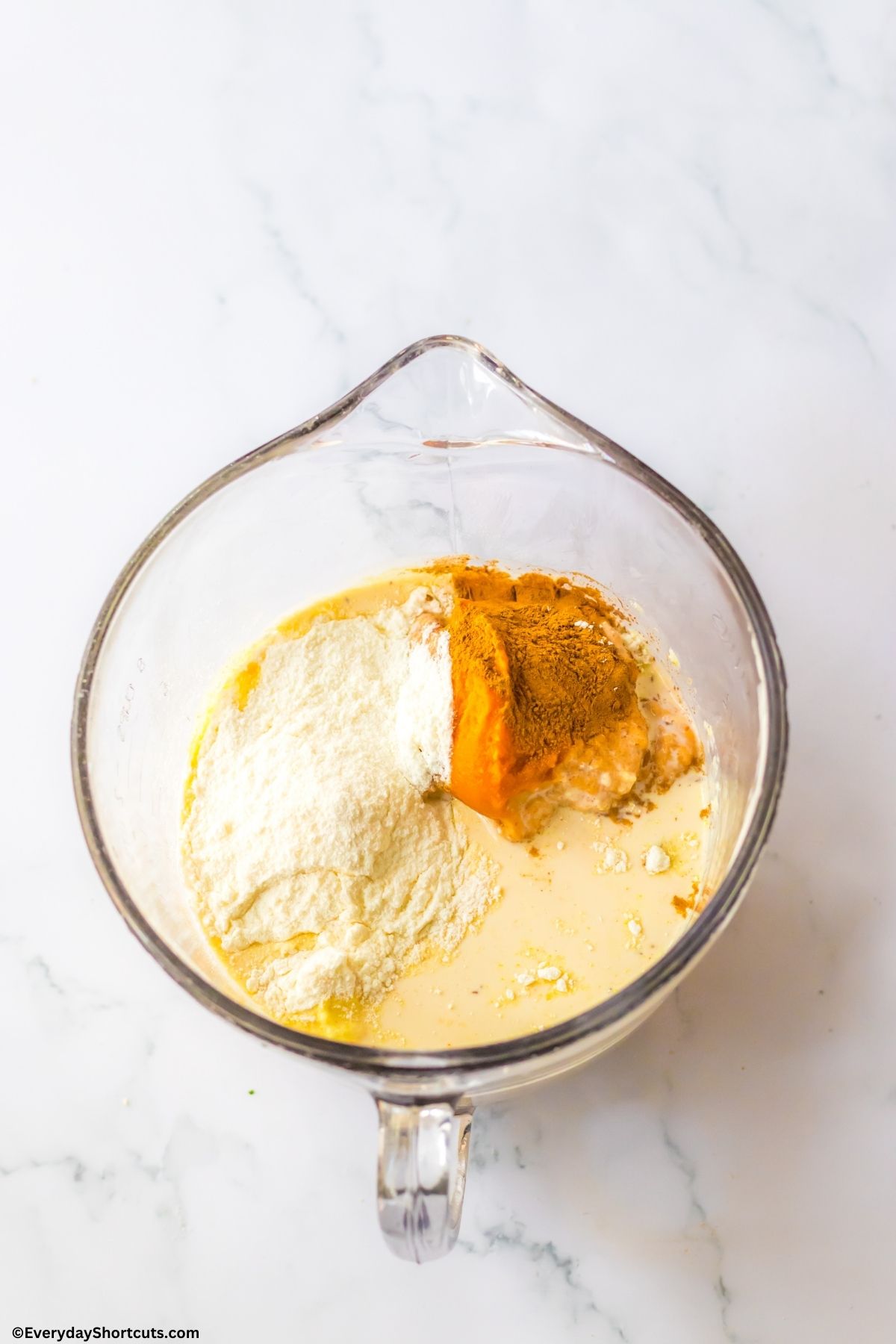 evaporated milk pumpkin puree instant pudding and pumpkin pie spice in a measuring cup