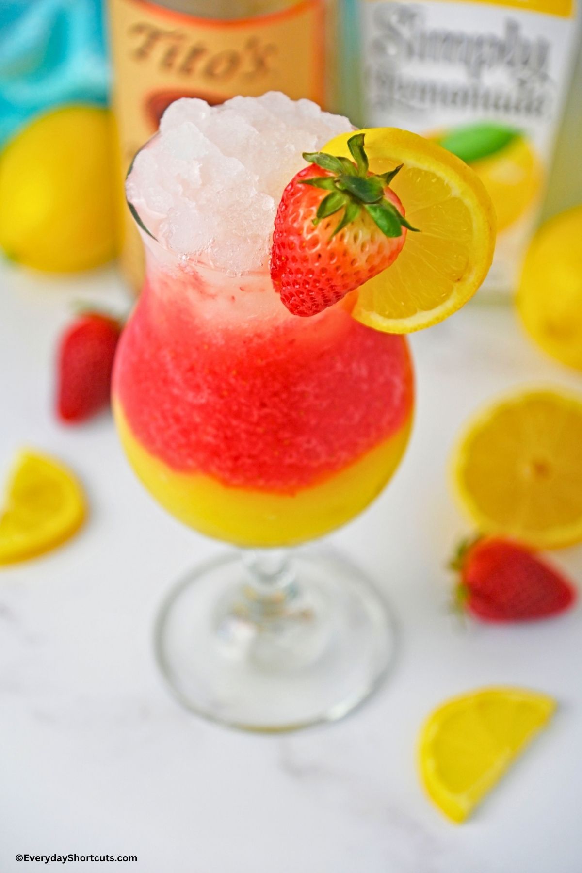 spiked ombre lemonade layered in a glass with a strawberry and lemon slice garnish