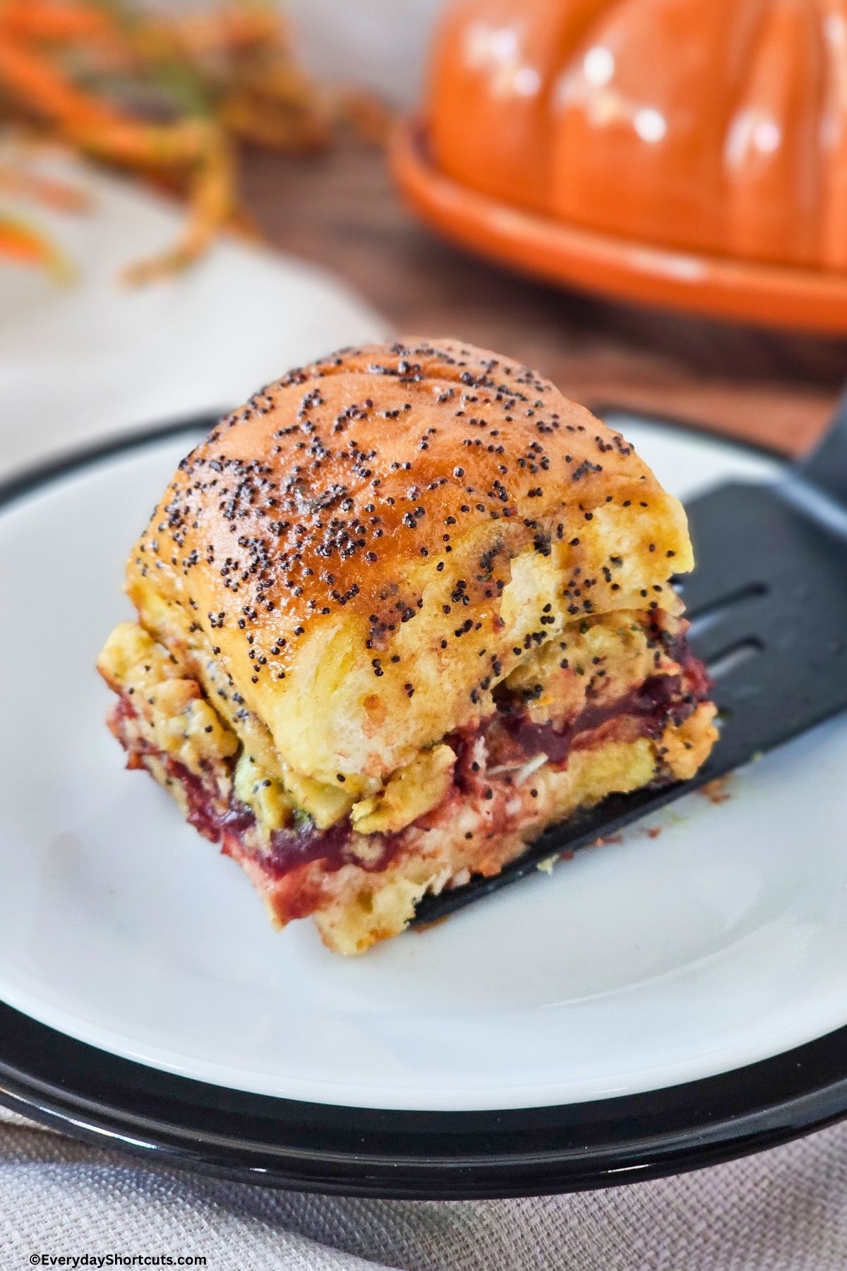 turkey sliders with cranberry sauce stuffing and cheese on a spatula
