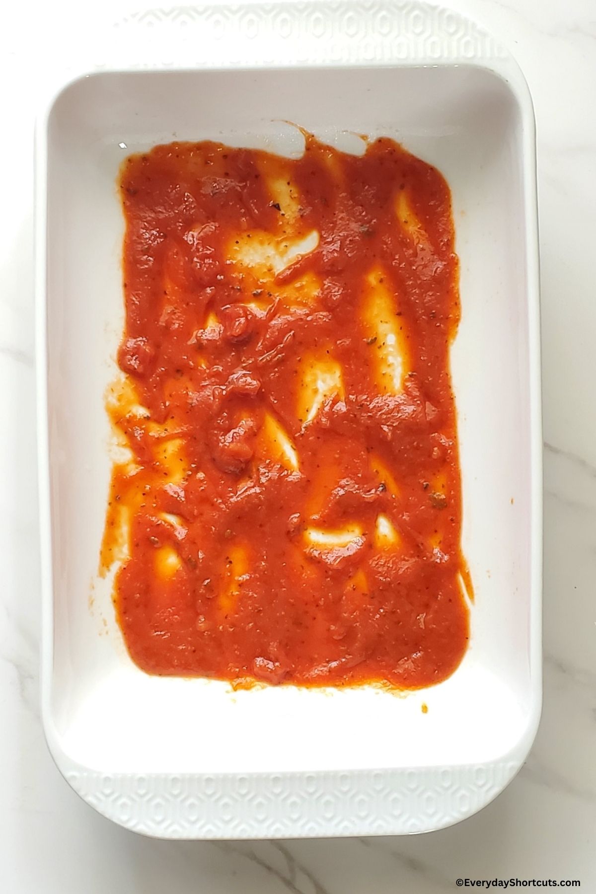 marinara sauce in the bottom of a baking dish