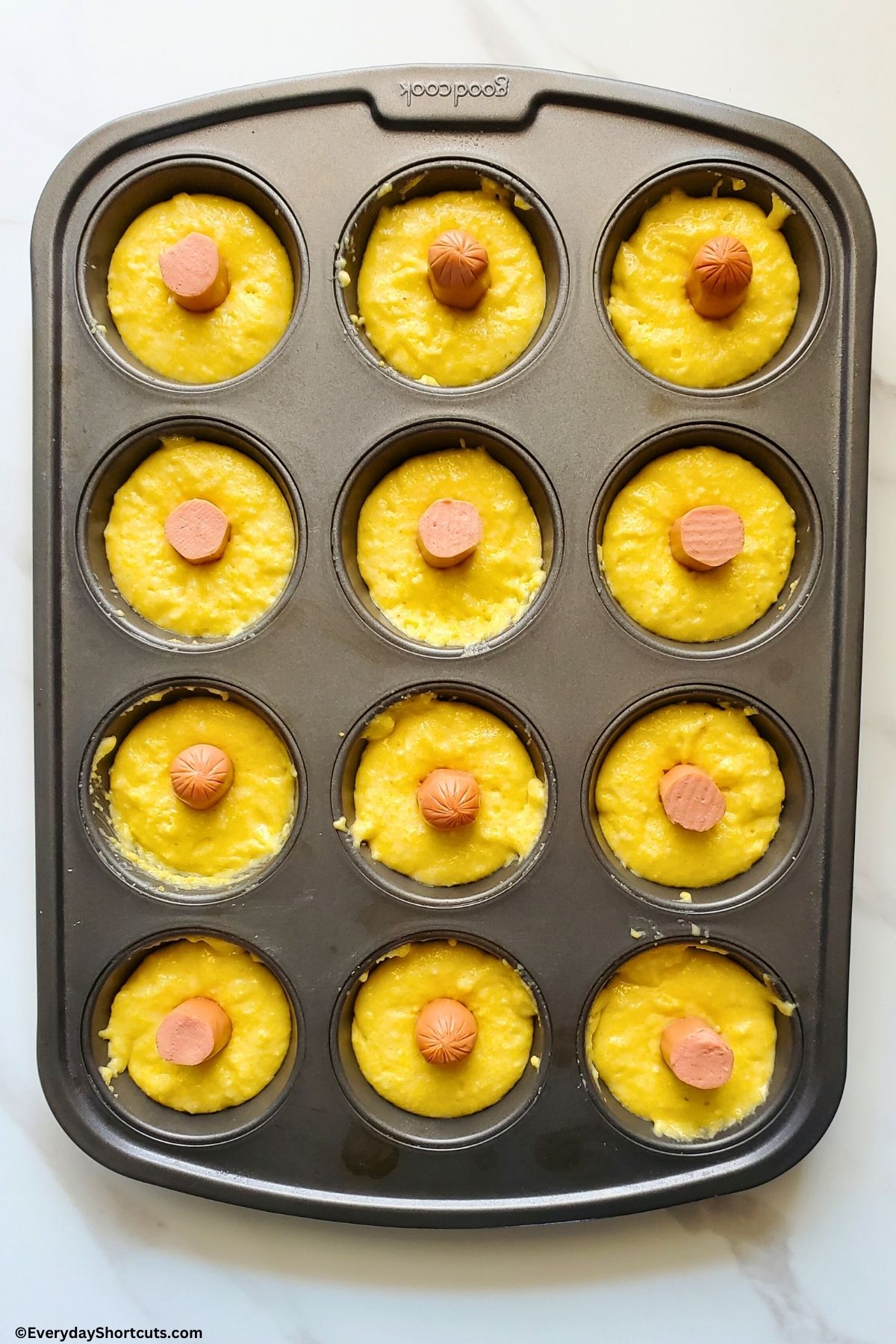corn dog batter and hot dogs in a muffin tin