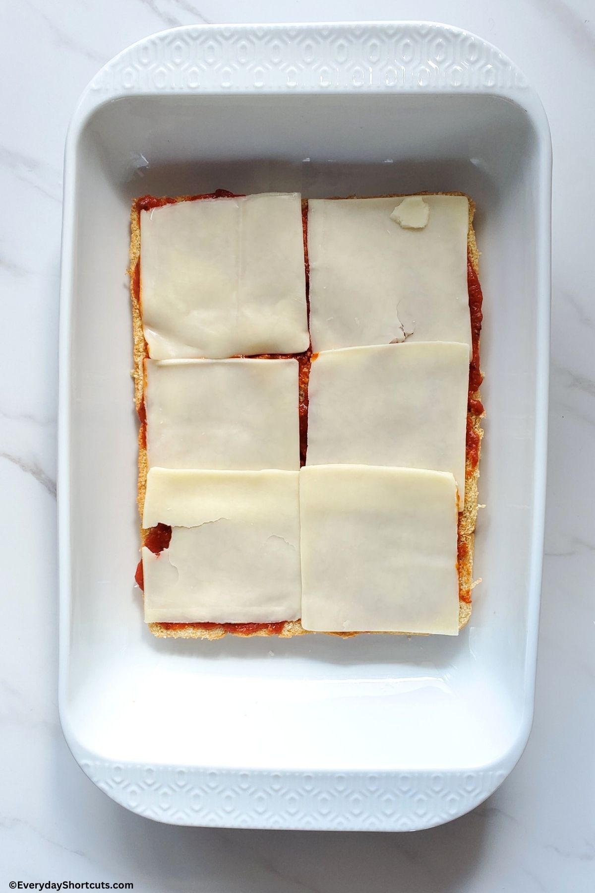 mozzarella cheese slices on top of marinara sauce on slider buns