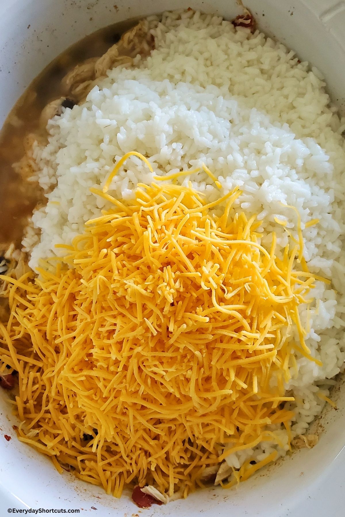 rice and cheese on top of southwest chicken in a slow cooker