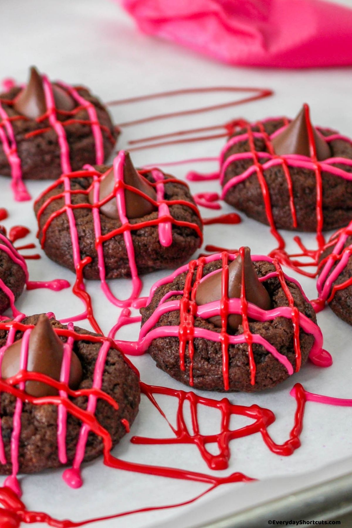 pink and red candy melts drizzled over top of chocolate kiss cookies