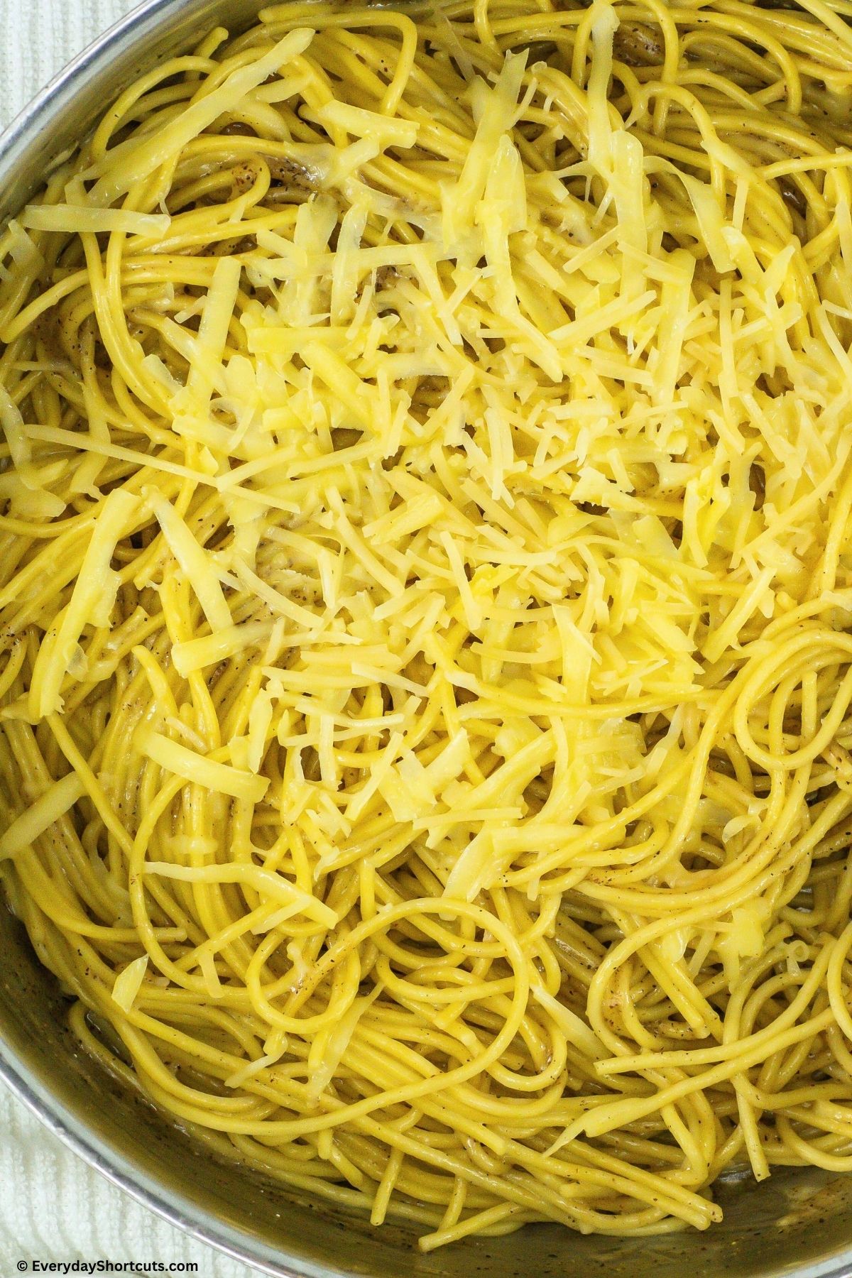 spaghetti noodles and cheeses in a pan