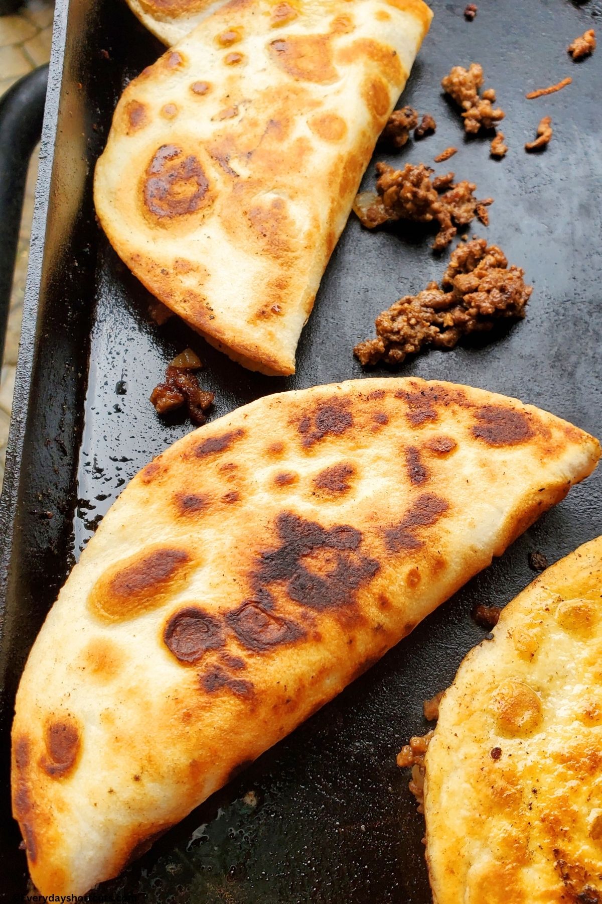 folded in half crispy beef tacos on a griddle