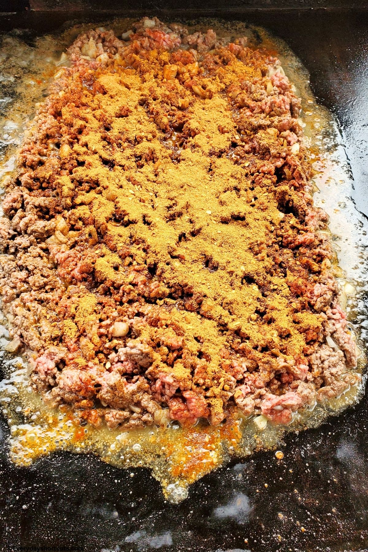 ground beef taco seasoning and onions on a griddle