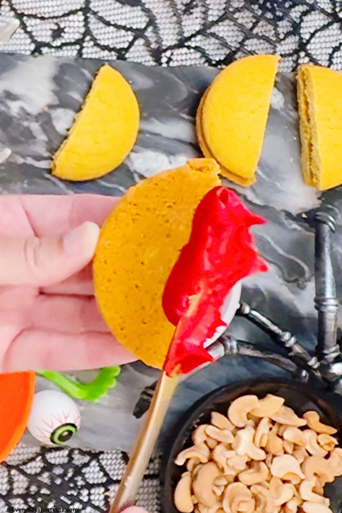 spreading red frosting on sugar cookie half
