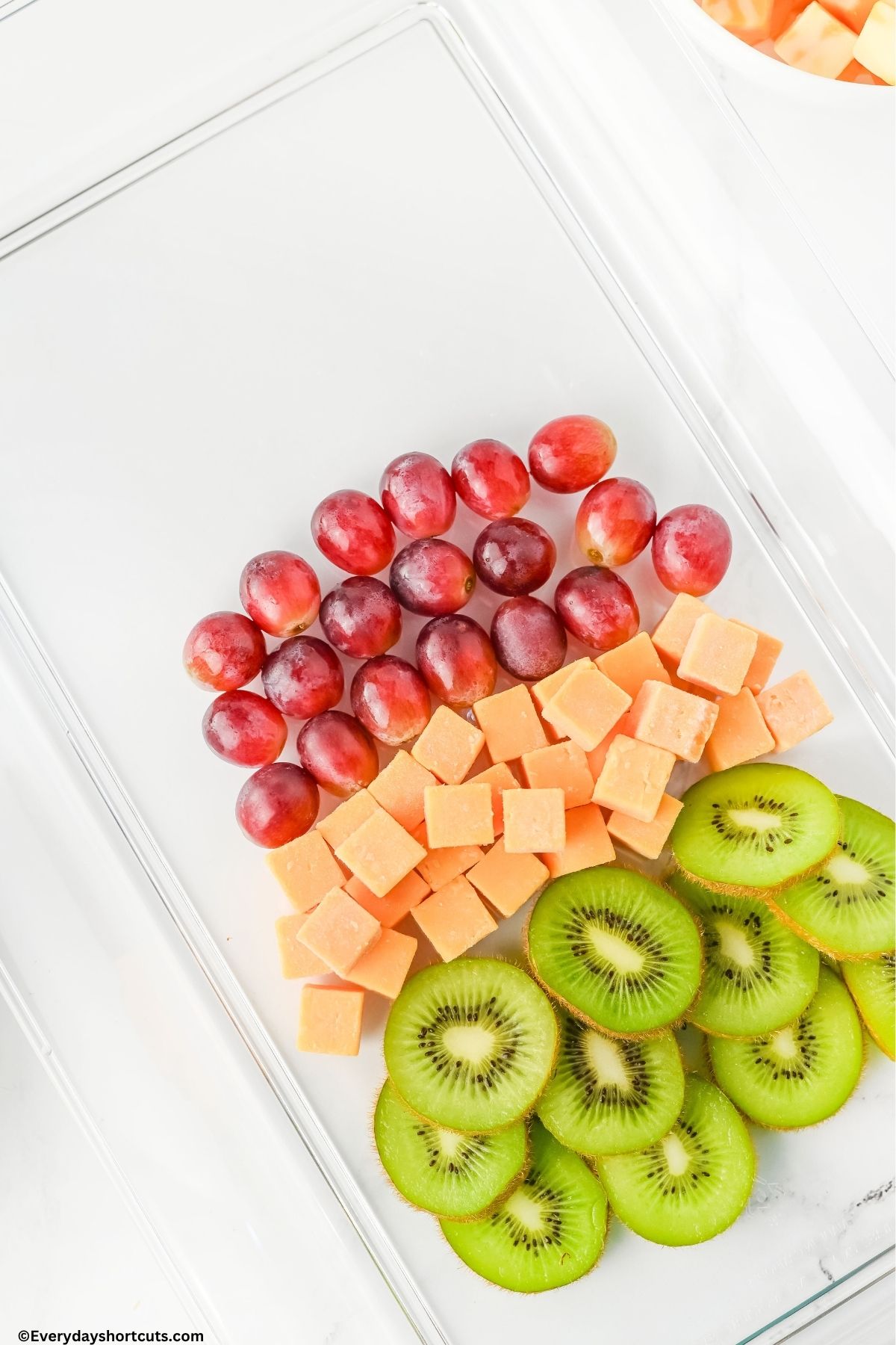 sliced kiwi cubed cheese and red grapes on a platter