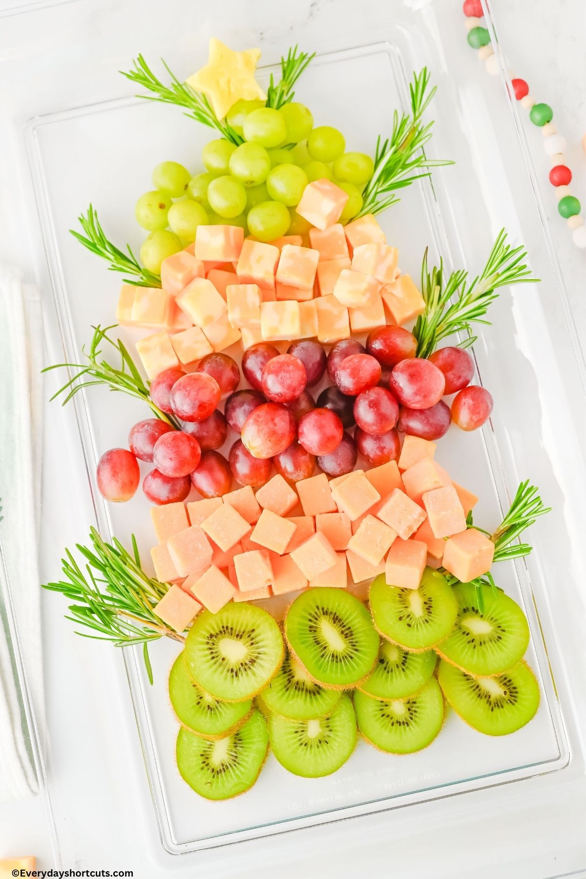 fruit and cheeses in the shape of a Christmas tree on a platter for the holiday
