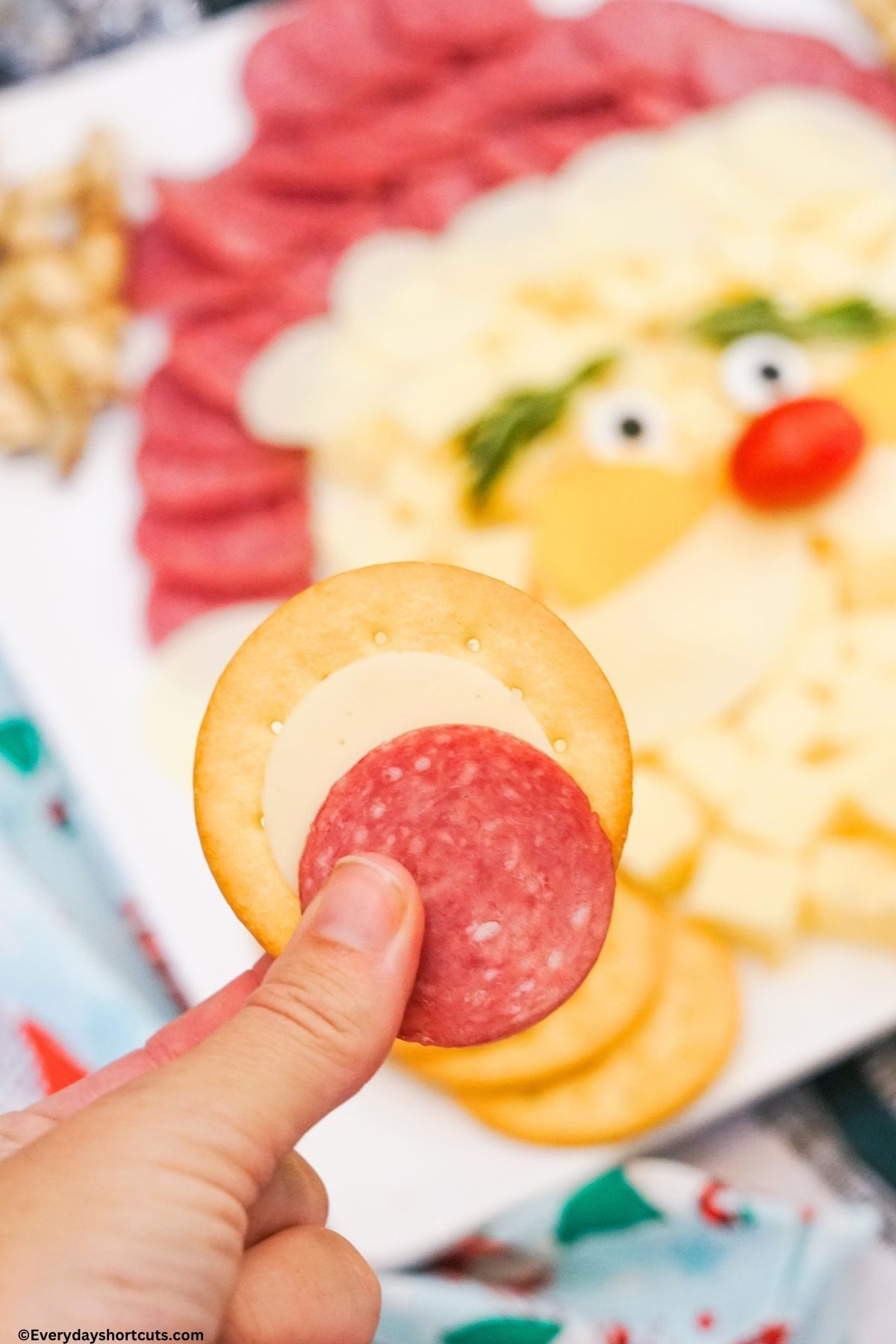 holding a meat cheese and cracker