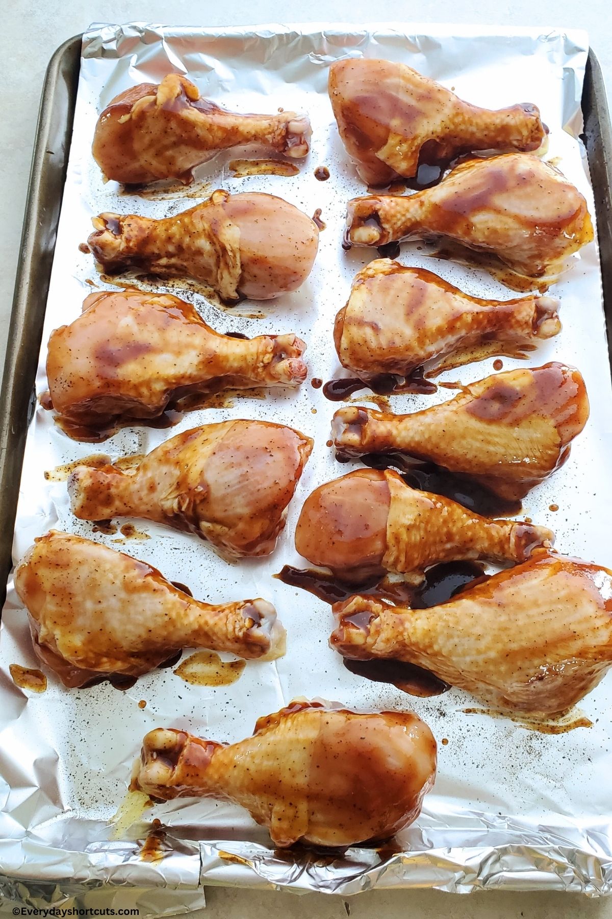 raw chicken marinated in bbq sauce on a baking sheet