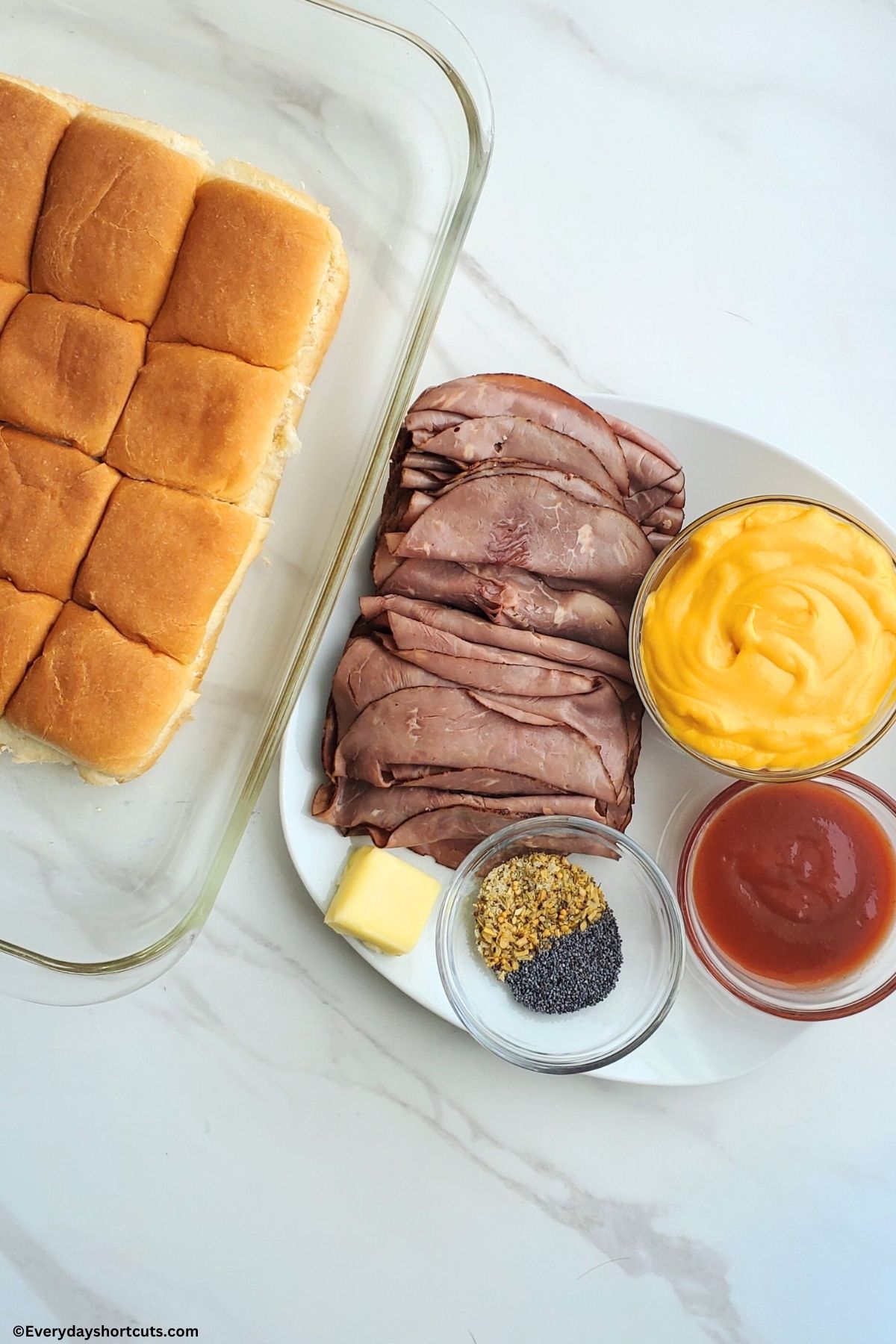 Hawaiian rolls in a baking dish roast beef cheese sauce butter Arby's sauce poppy seeds and dried onions on a white plate