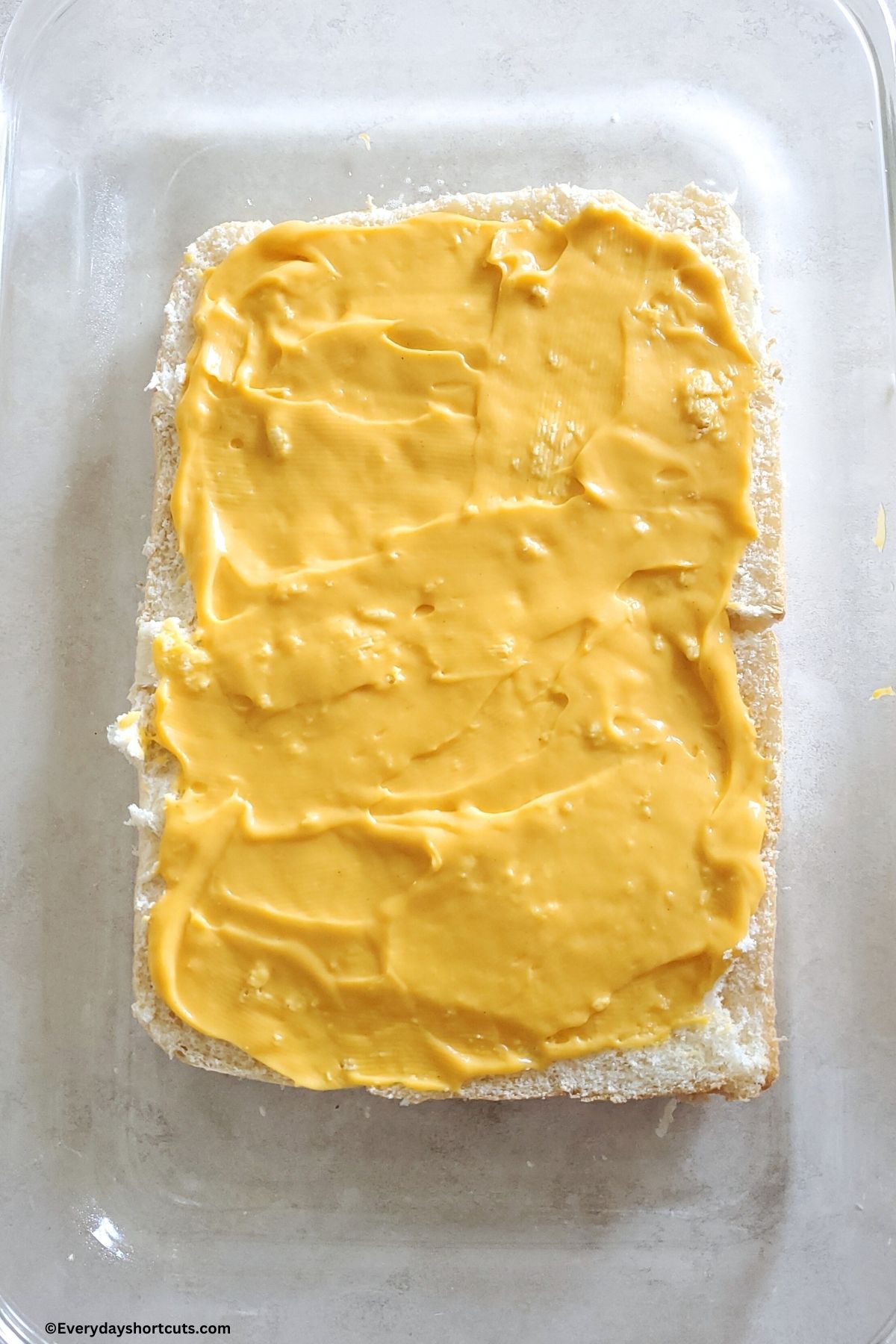 cheese sauce spread evenly on bottom half of Hawaiian rolls in a baking dish