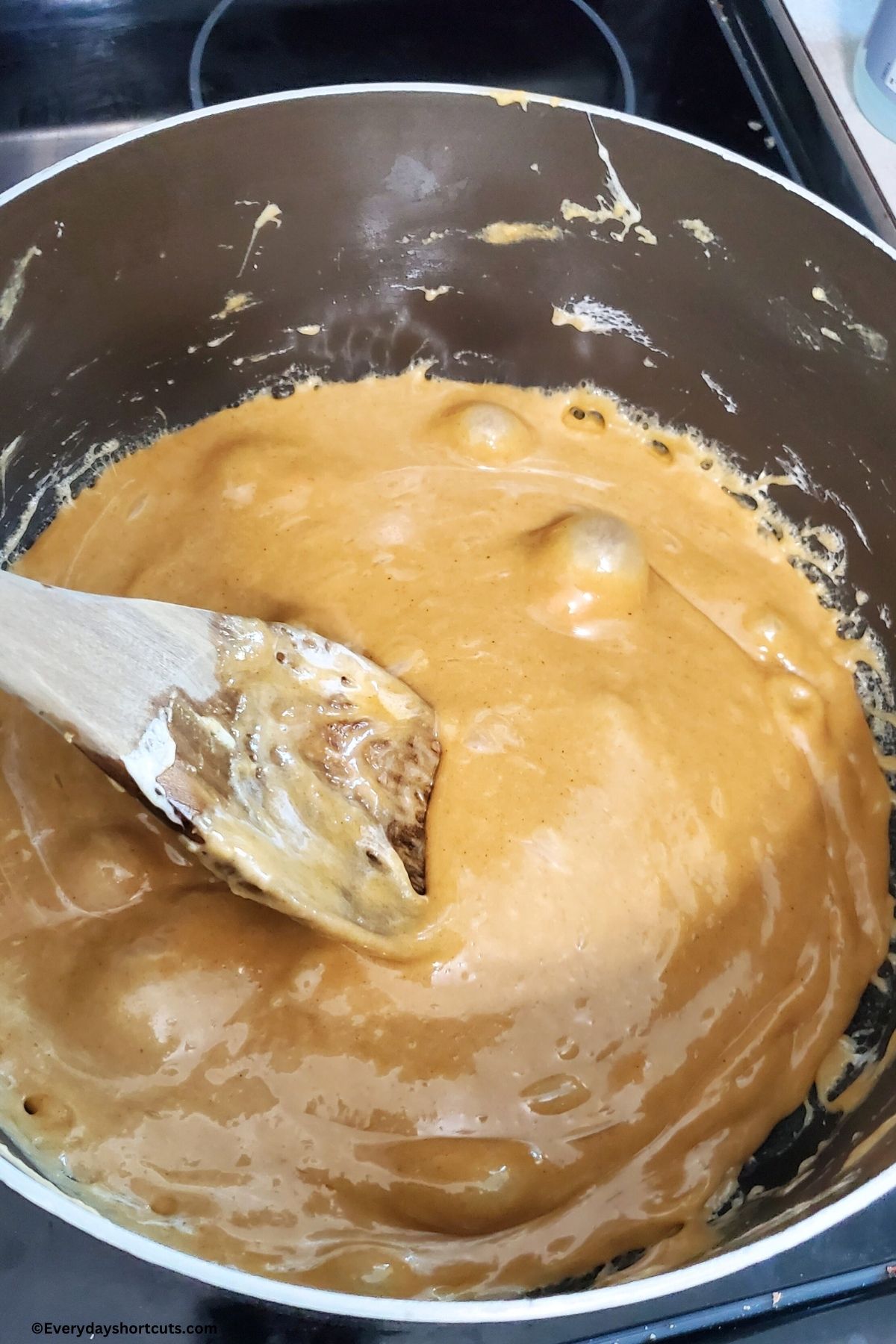 melted peanut butter with marshmallows and butter in a pot stirred with a wooden spoon