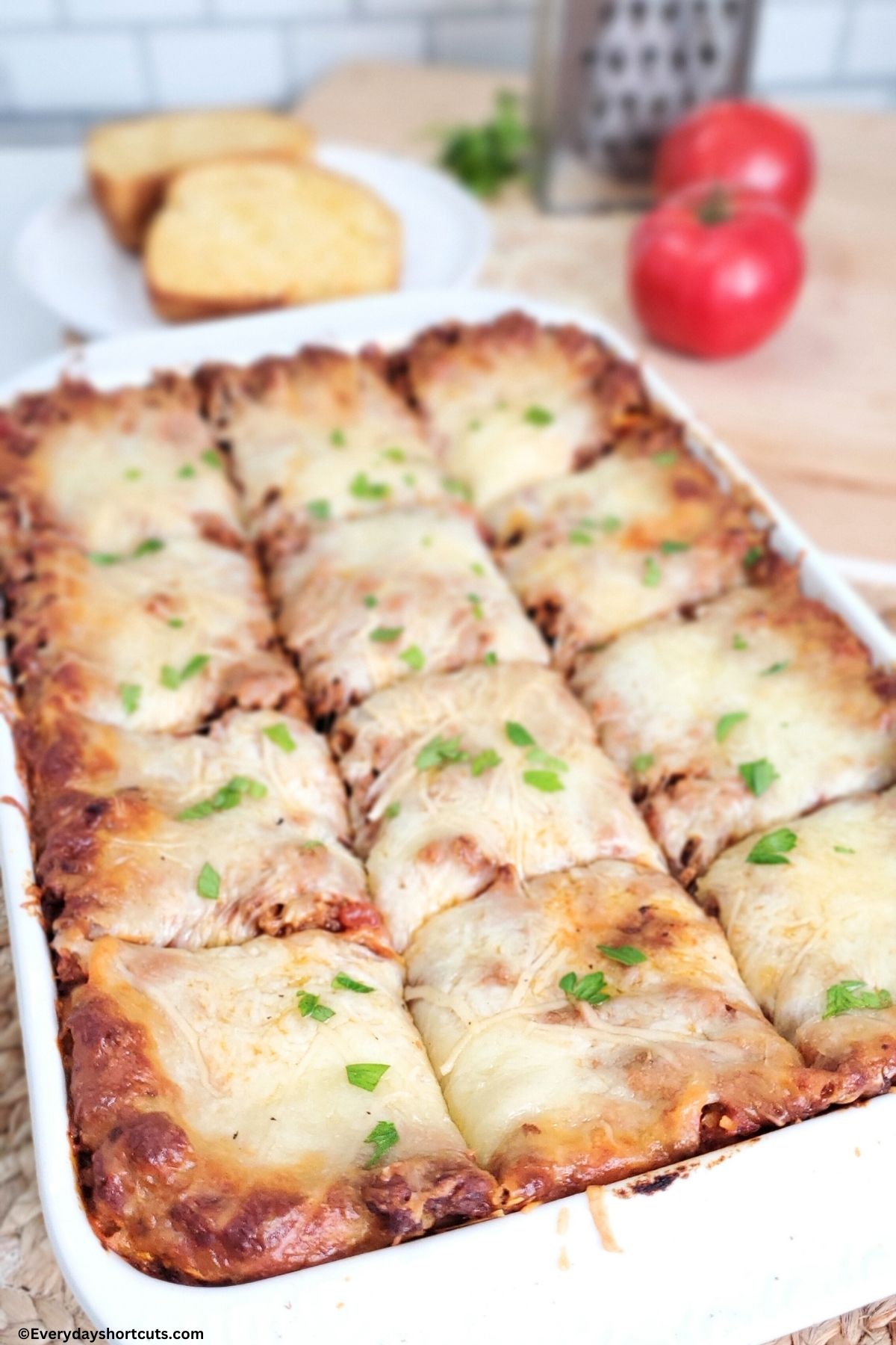 long noodle casserole cut into 12 squares in a white baking dish