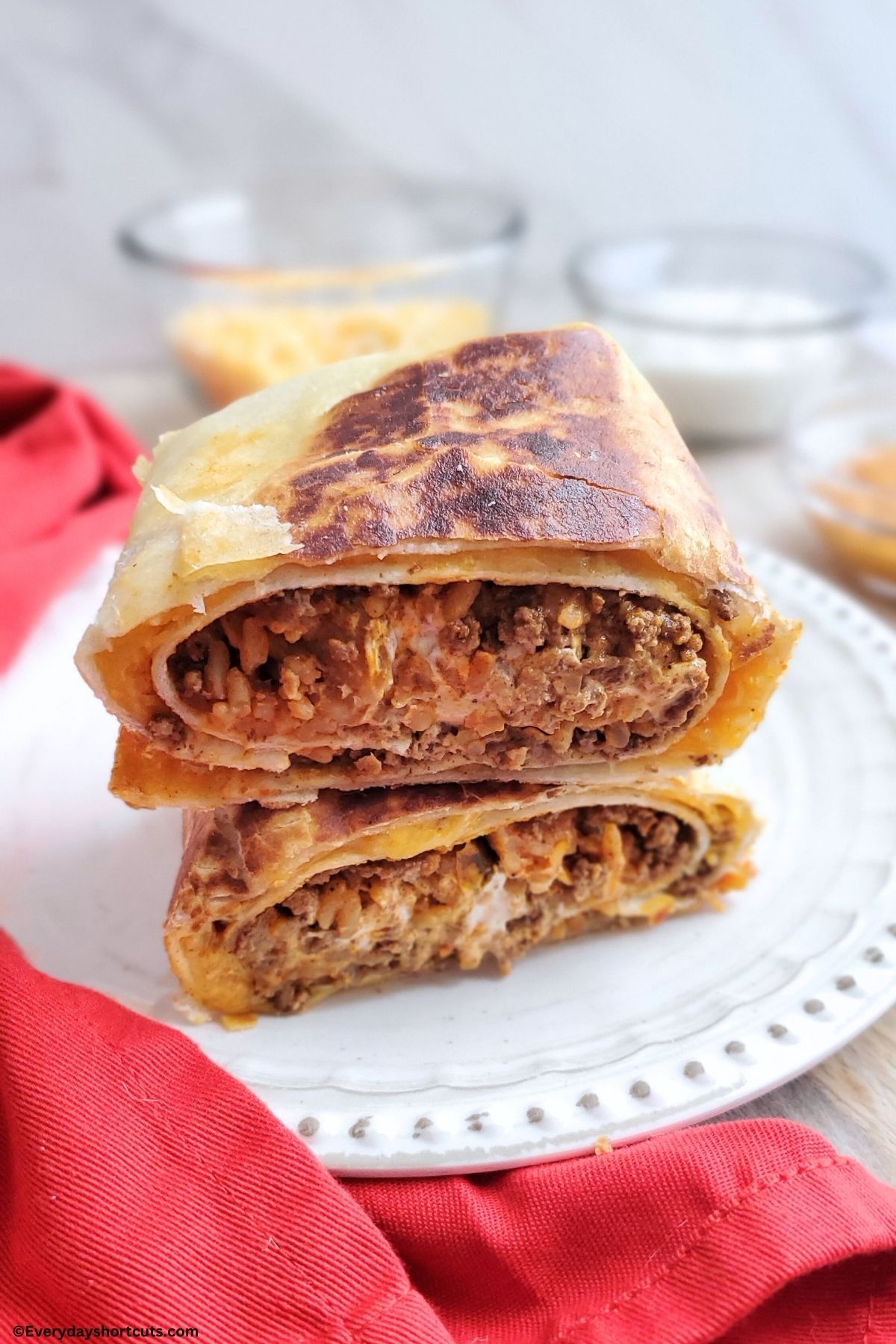 sliced in half beef Quesarito on a white plate with a red napkin