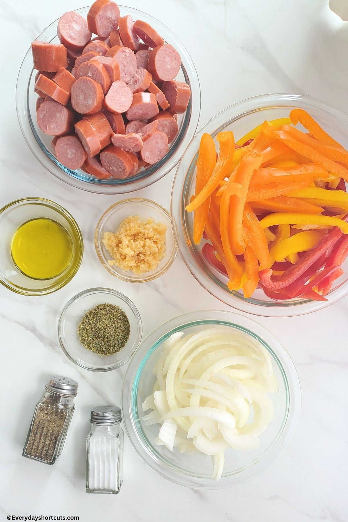prepped ingredients of sweet peppers sausage minced garlic olive oil Italian seasoning salt and pepper in bowls