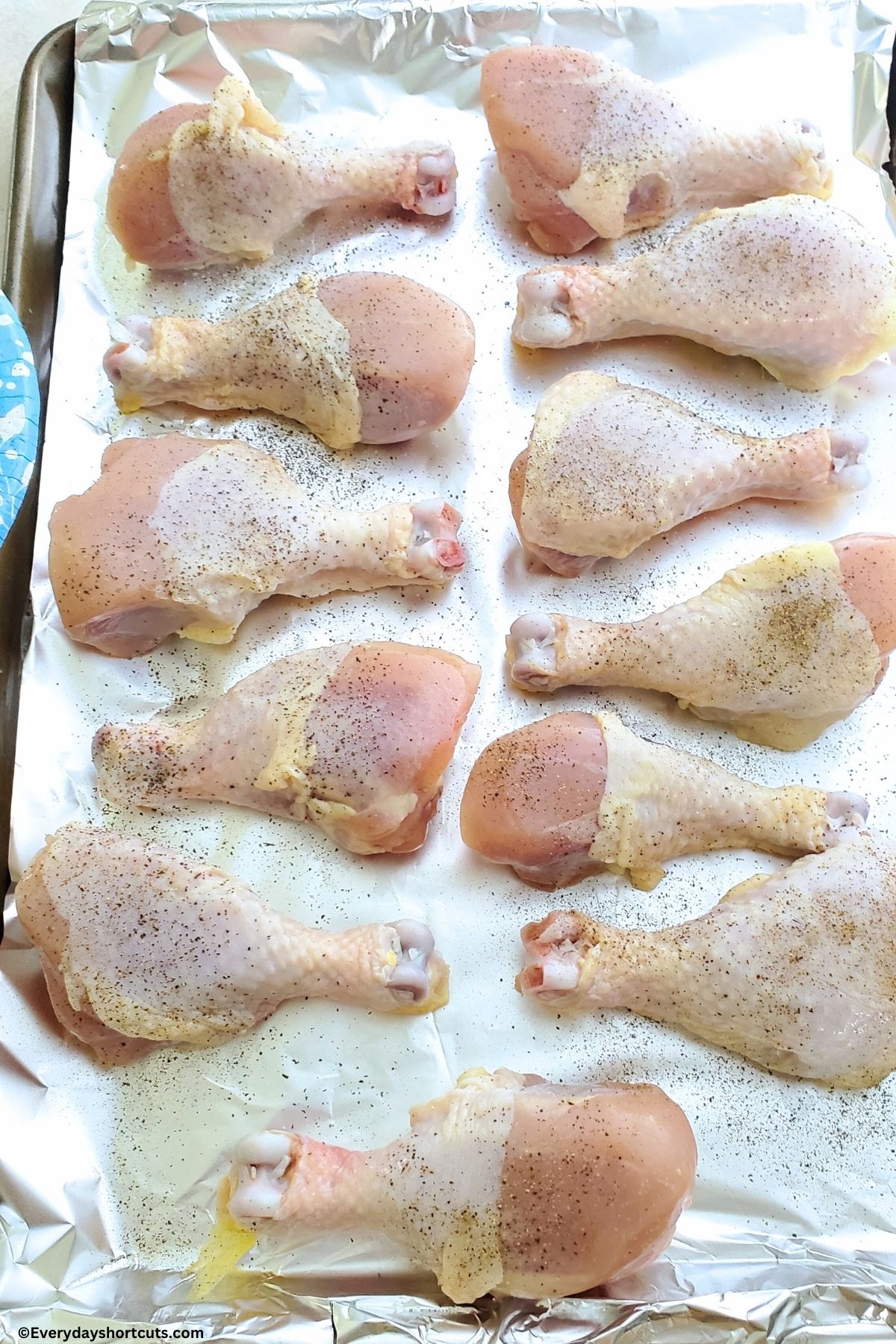 chicken drumsticks on a lined with foil baking sheet seasoned with salt and pepper