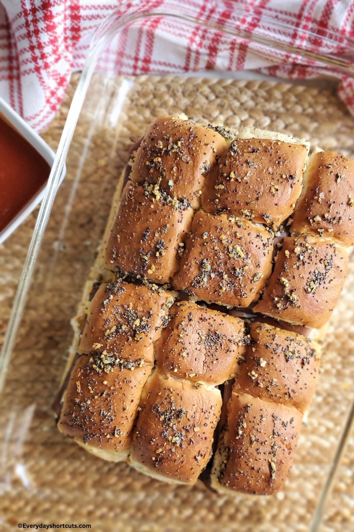baked cheddar and beef sliders in a baking dish next to a bowl of Arby's sauce