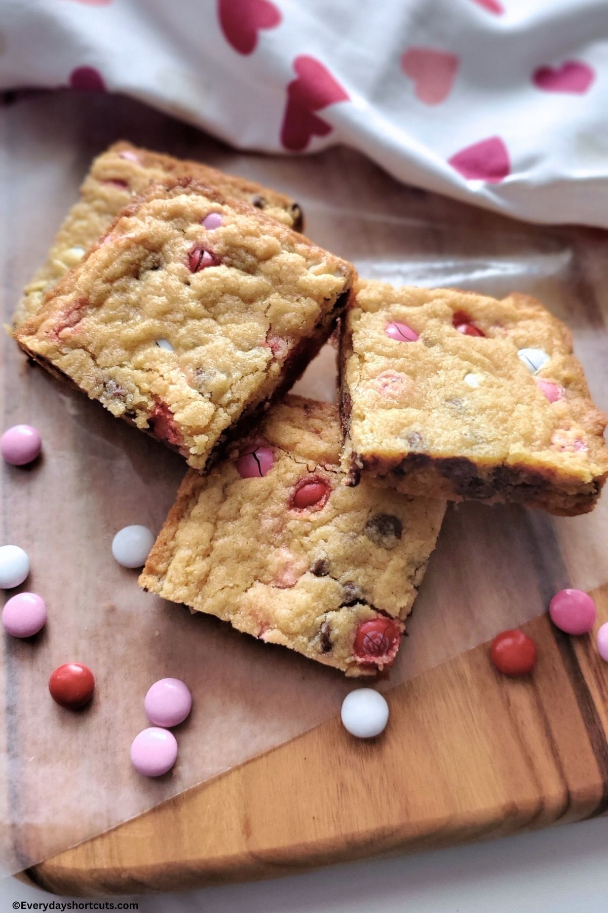 M&M Valentine chocolate chip cookie bars cut into squares on a wood cutting board
