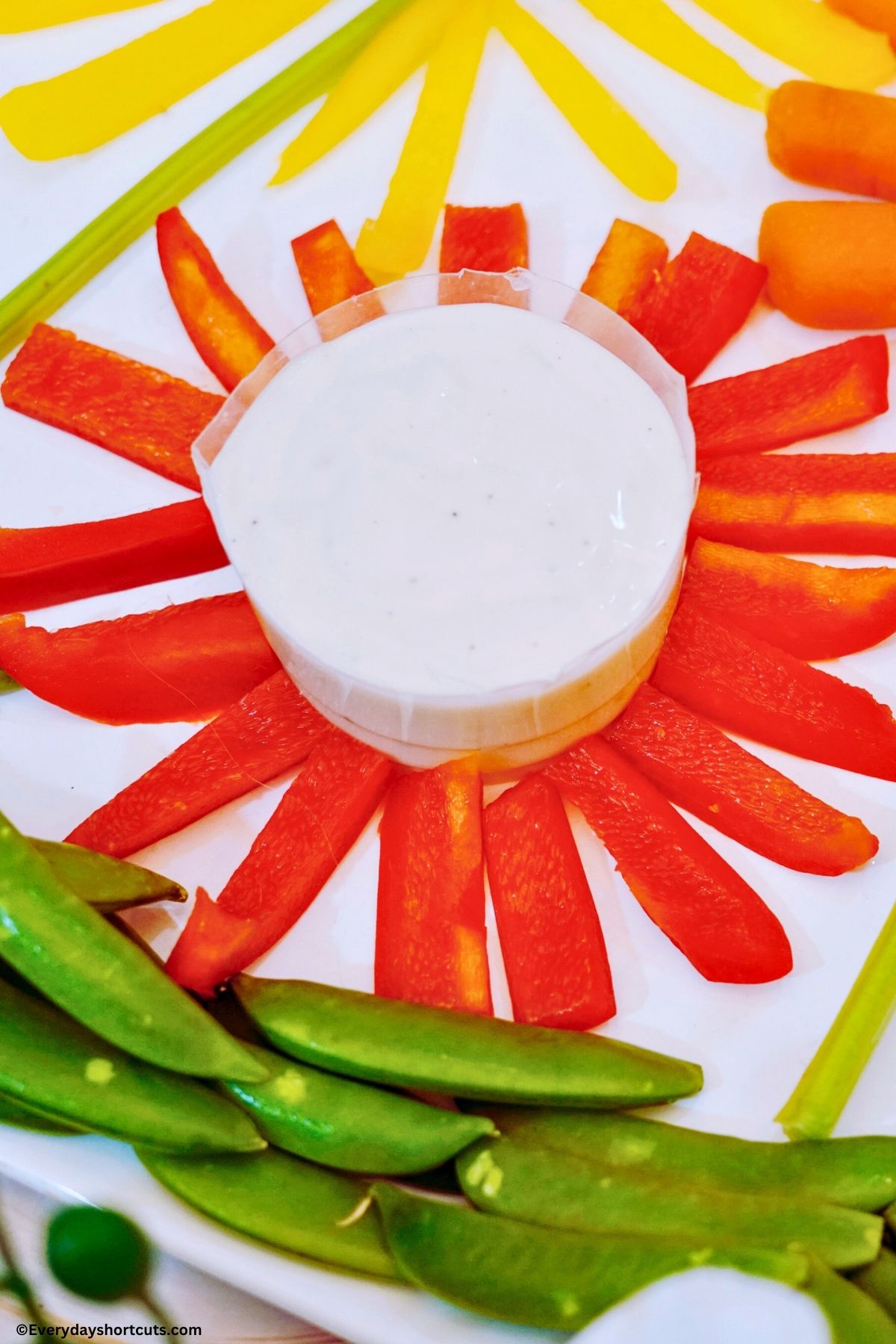 red bell pepper strips in a circular pattern with a bowl of ranch dressing in the middle of it