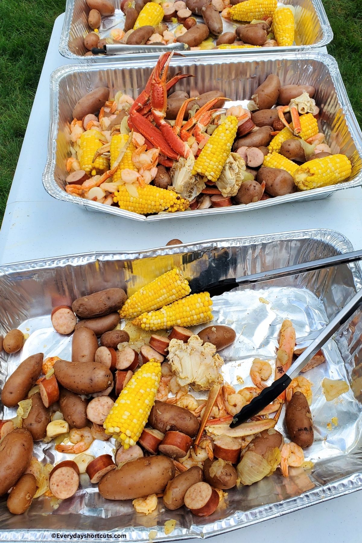 three aluminum tray with seafood boil mixture in each one on a table