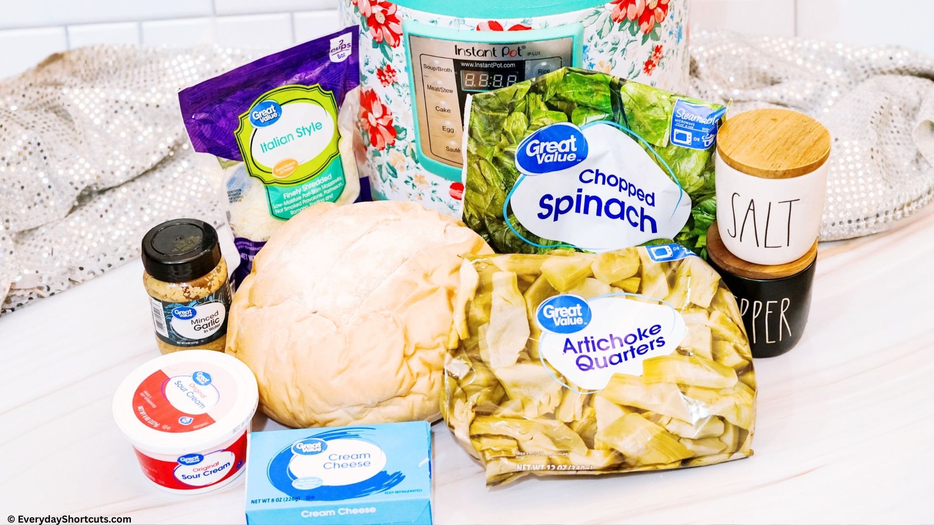 frozen bagged spinach frozen bagged artichoke round loaf bread Italian shredded blend cheese minced garlic sour cream salt and pepper shaker cream cheese on a white board