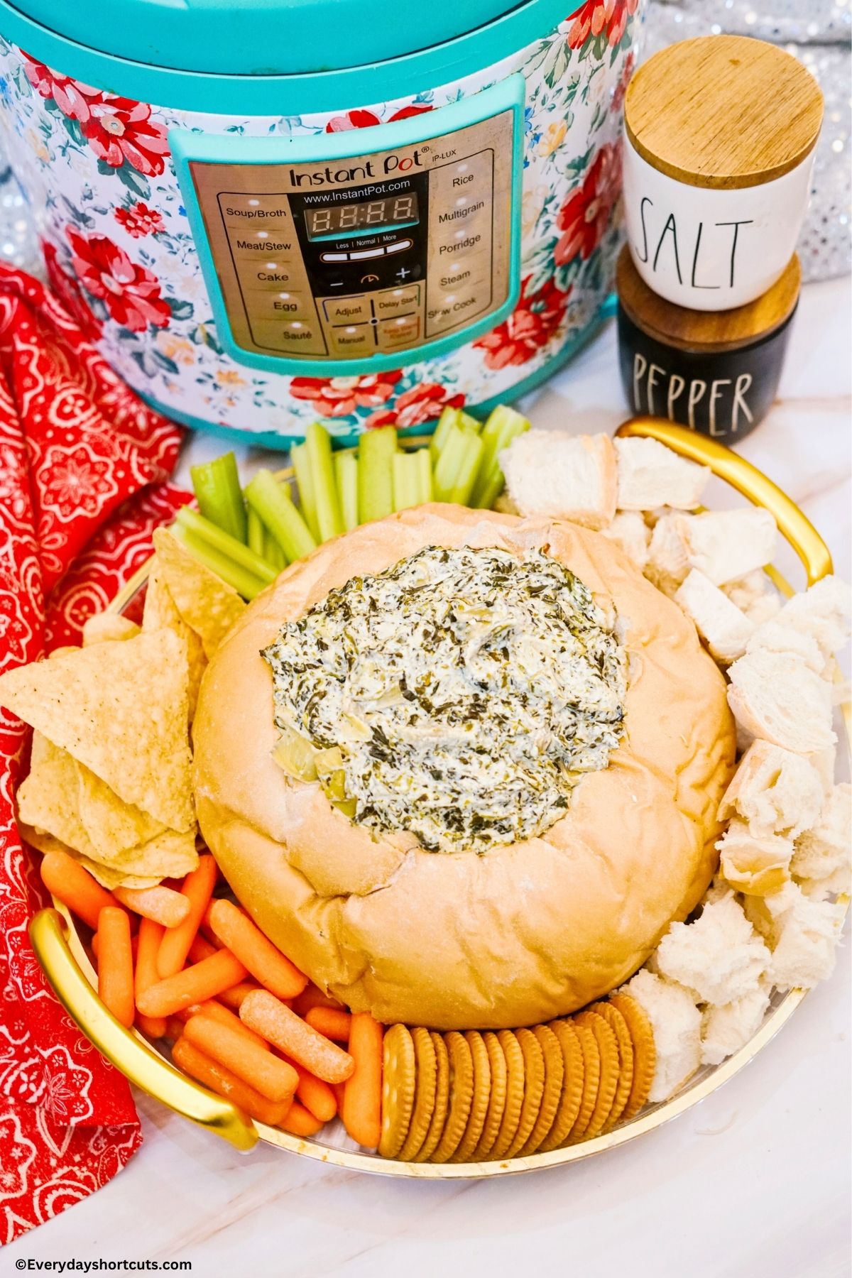 spinach artichoke dip in a bread bowl with veggies, bread and crackers surrounding it next to an Instant pot