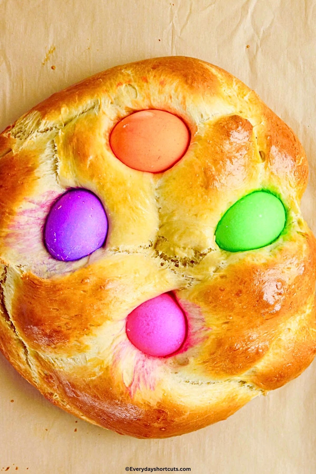 baked Easter bread with colored eggs on Parchment paper