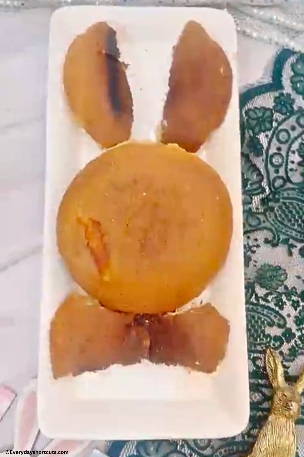 Place the round cake in the center of the platter add the two ears on top and bow tie at the bottom