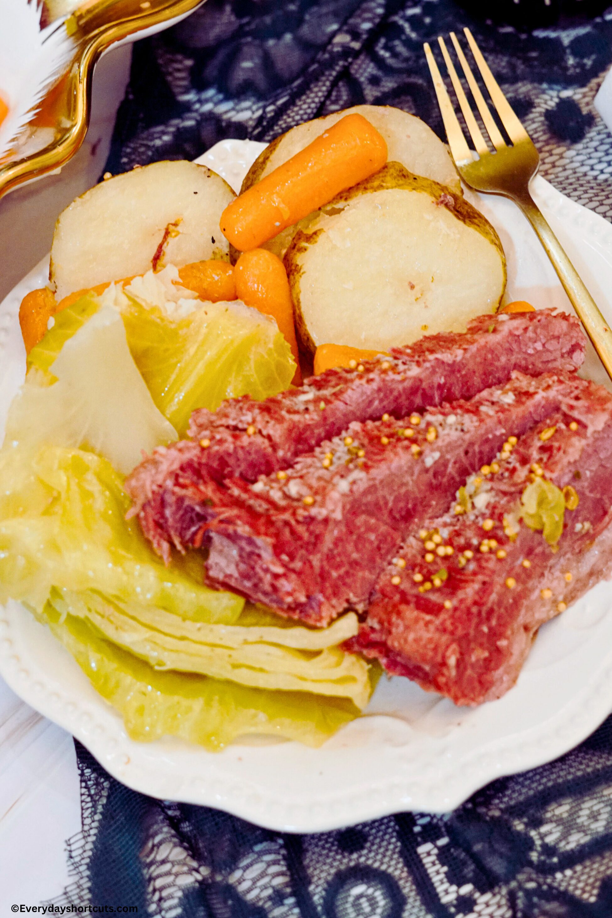 corned beef cabbage potatoes carrots on a white plate with a gold fork