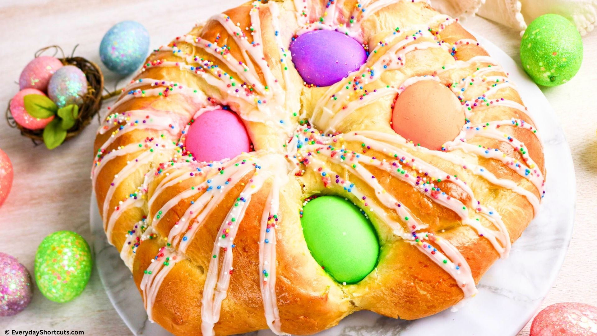 closeup shot of Easter bread with 4 colored eggs, icing and sprinkles on top