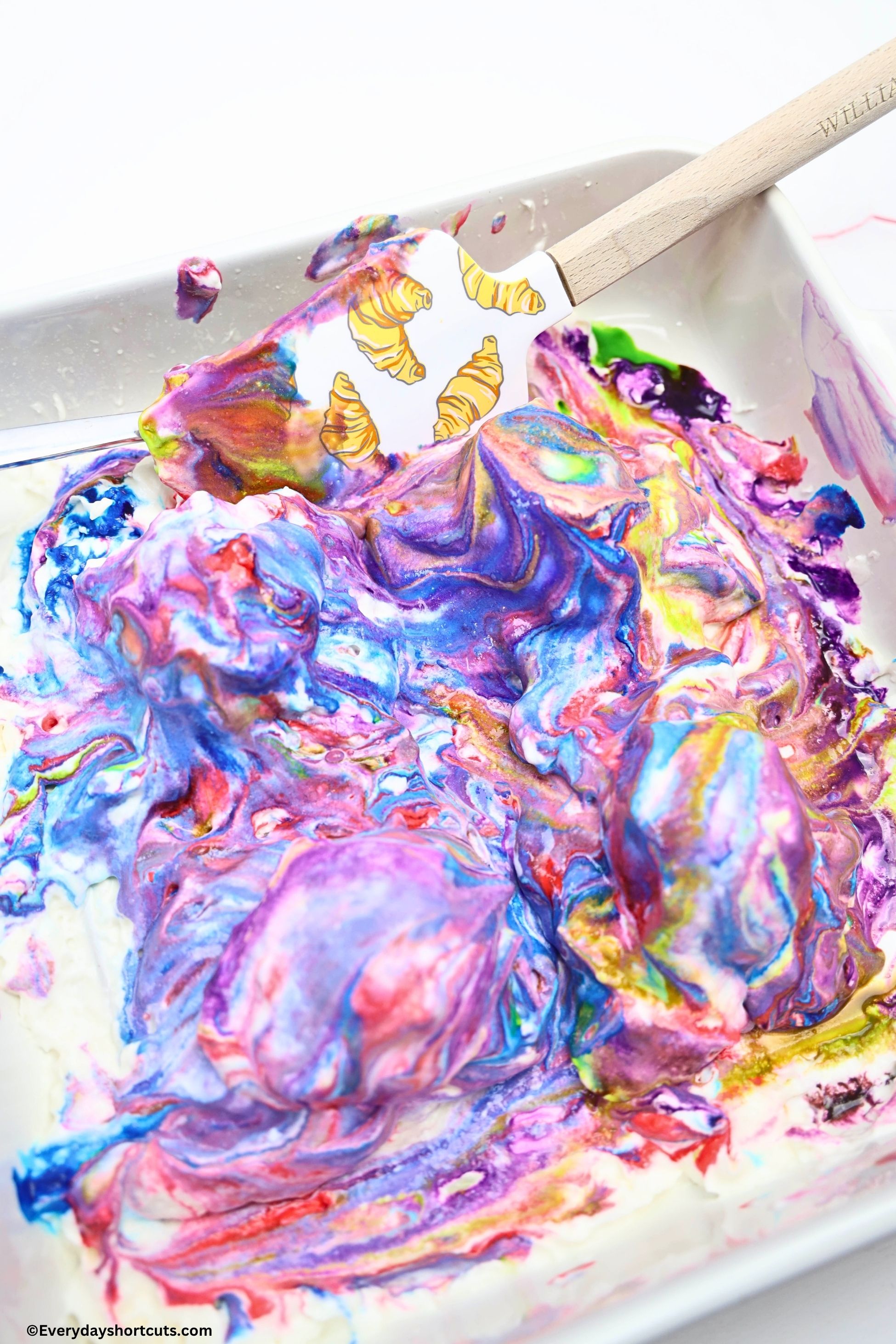 eggs covered in food dyed whipped cream in a white baking dish